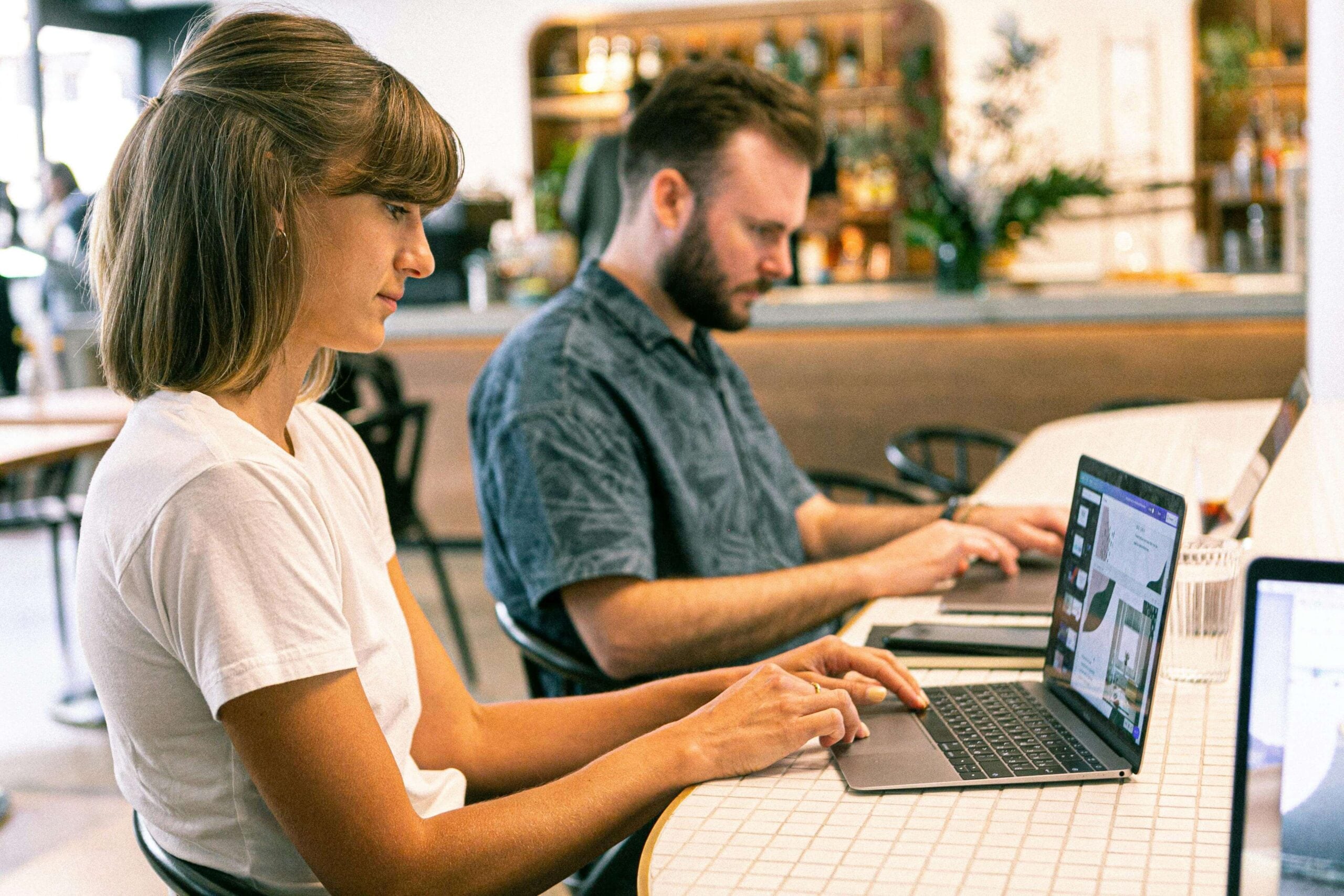 two people working at a desk on laptops