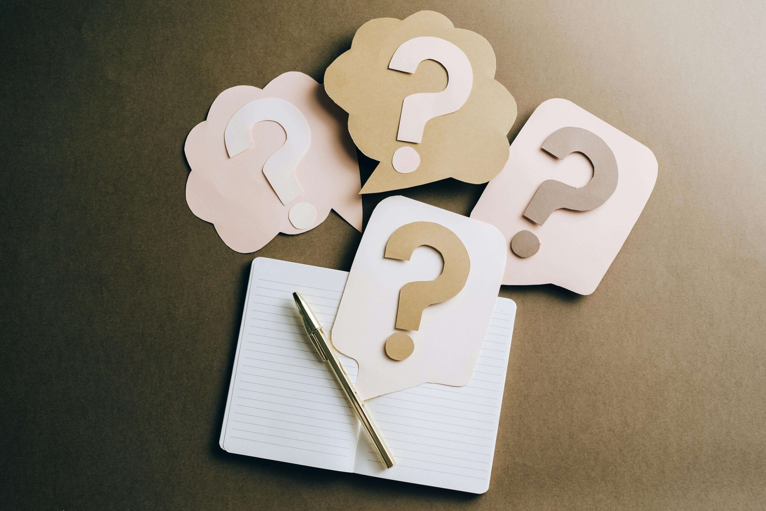 pen and paper with question marks around it